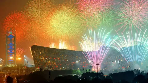 Spectacular fireworks exploding over Beijing's Bird's Nest stadium during the Paralympic opening ceremony, with colorful lights reflecting off the iconic architecture